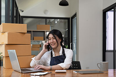 Business and Management Pathway young business owner on the phone surrounded by boxes