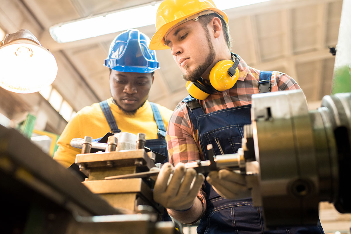 Industrial Technology Pathway two machinists wearing hardhats and working